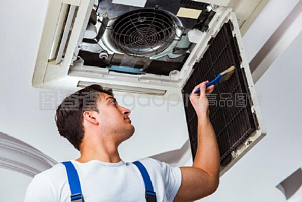 修理天花板空調設備的工人